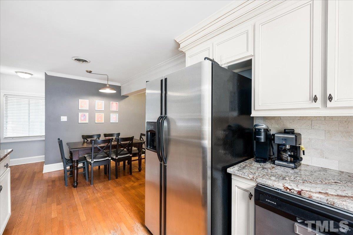 3225 Merriman Avenue Raleigh, NC 27607 - Photo 9 of 19 a kitchen with stainless steel appliances granite countertop a refrigerator a stove top oven a dining table and chairs with wooden floor