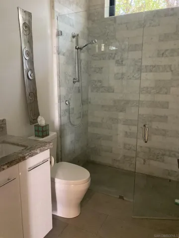 a bathroom with a granite countertop sink a toilet and shower