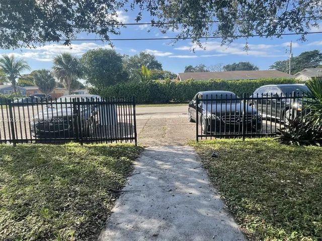 a view of a yard in front of a house with wooden fence
