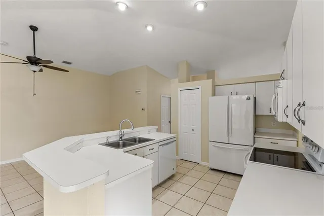 a kitchen that has a sink a refrigerator and a stove top oven