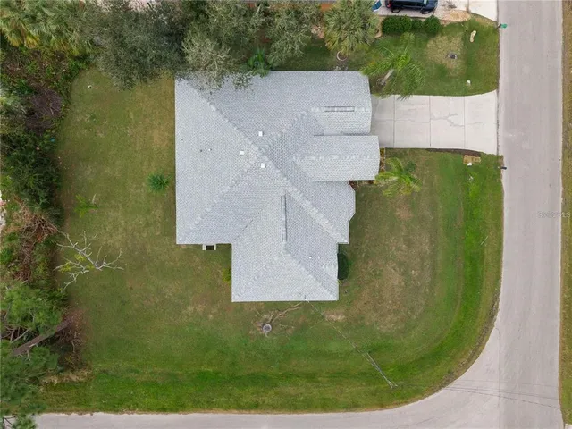 an aerial view of a house with a yard and trees all around