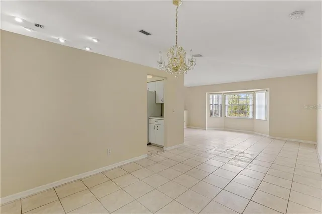 a view of a livingroom with a chandelier fan and kitchen view