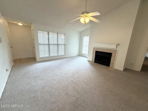 a view of an empty room with a fireplace and a window