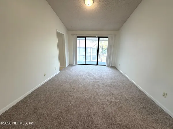 a view of a big room with windows and chandelier fan