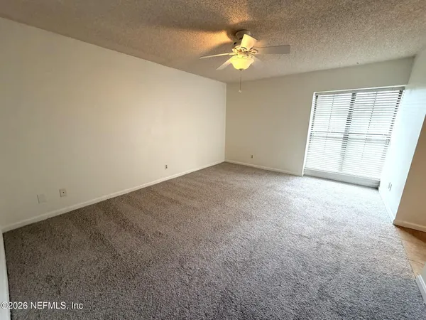 an empty room with windows and ceiling fan