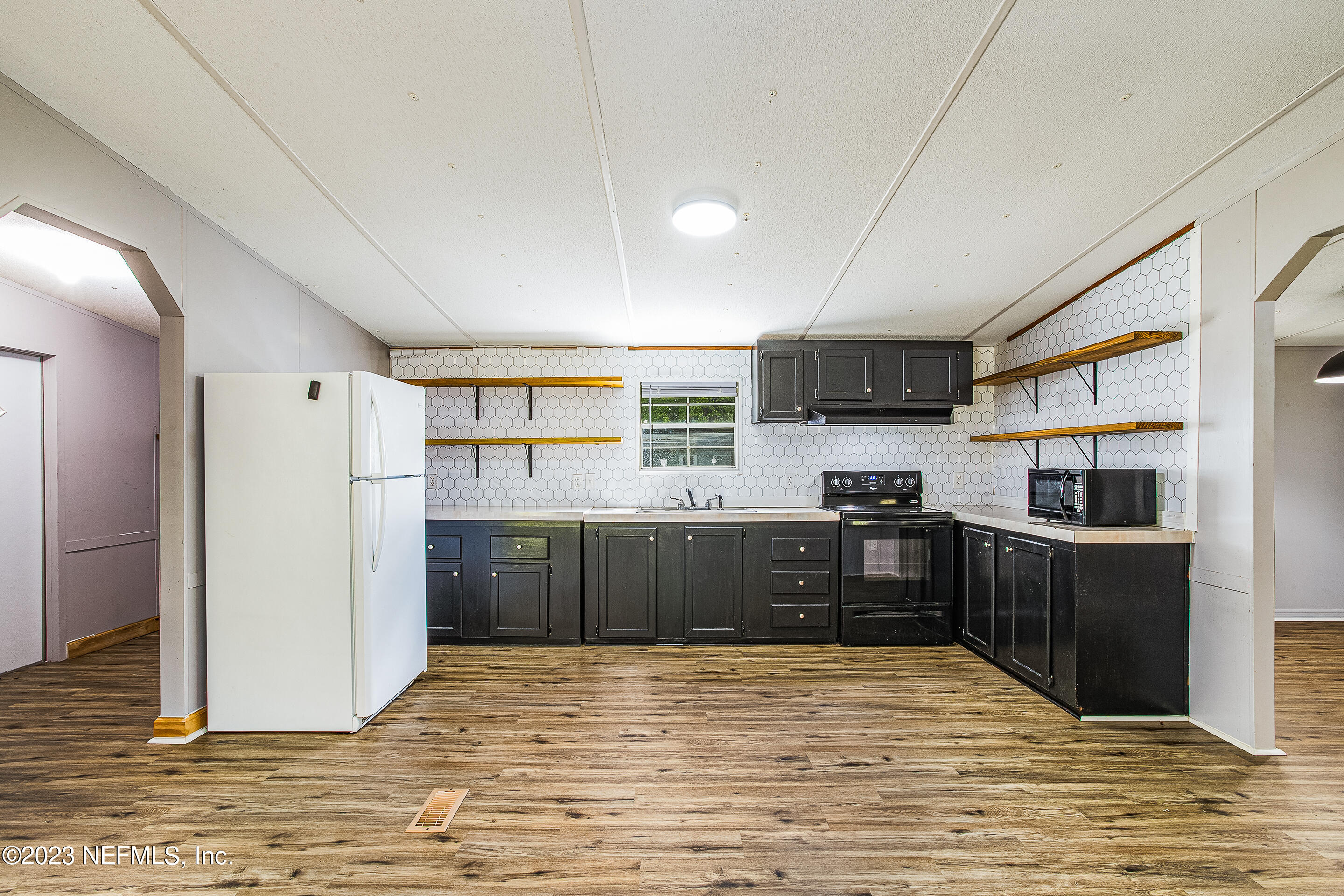 35157 Goodbread Road Callahan, FL 32011 - Photo 16 of 38 a kitchen with stainless steel appliances wooden cabinets a stove top oven a sink dishwasher and wooden floor