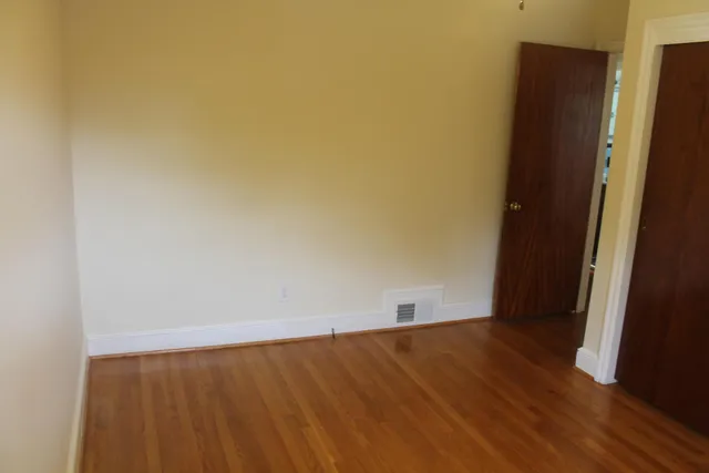 an empty room with wooden floor and cabinet