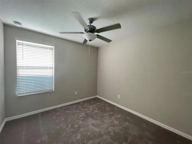 an empty room with a window and a fan