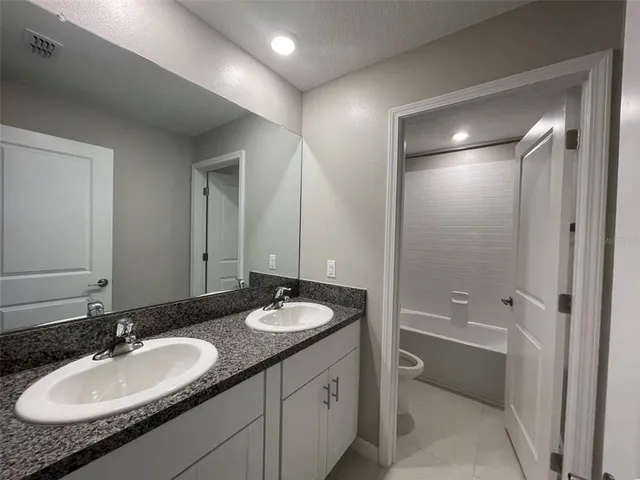 a bathroom with a sink double vanity granite tub and shower
