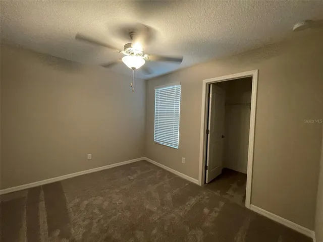 an empty room with a chandelier fan and a bathroom