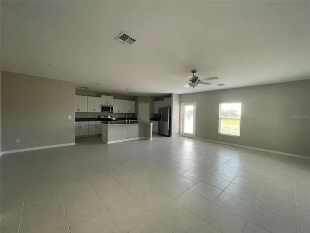 a view of empty room with kitchen and window