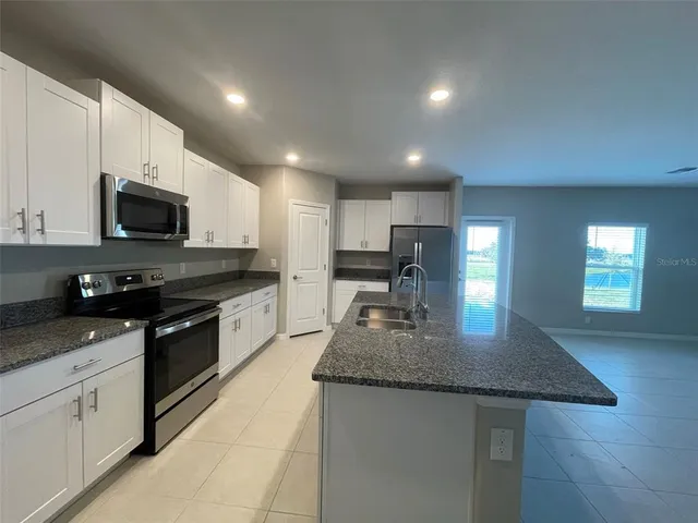 a kitchen with stainless steel appliances granite countertop a sink a stove and microwave