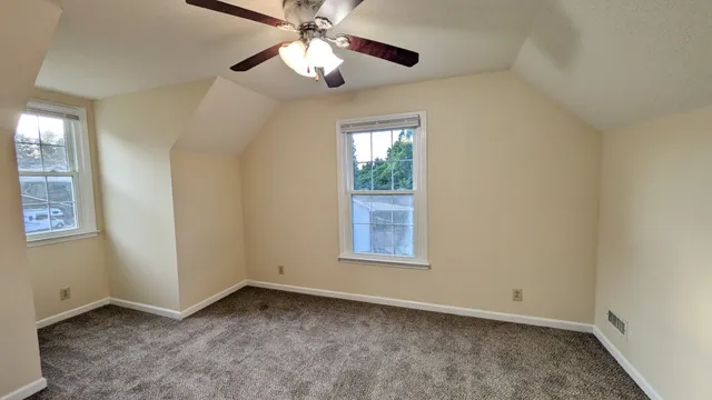 an empty room with windows and fan