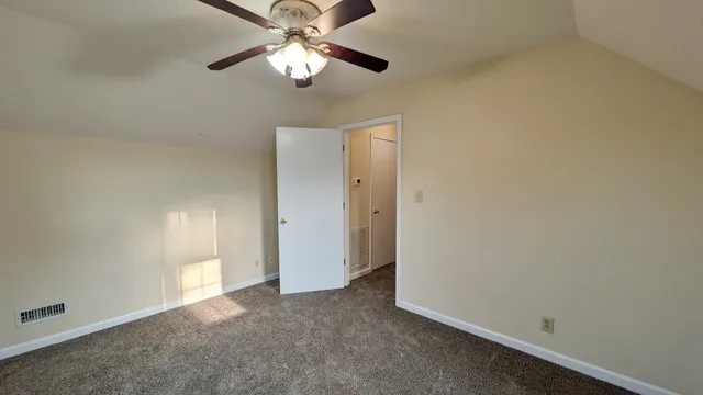 an empty room with a chandelier fan and a ceiling fan