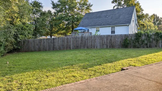 a view of a house with a yard and fence