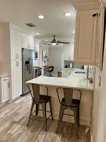 a kitchen with stainless steel appliances a dining table chairs and sink
