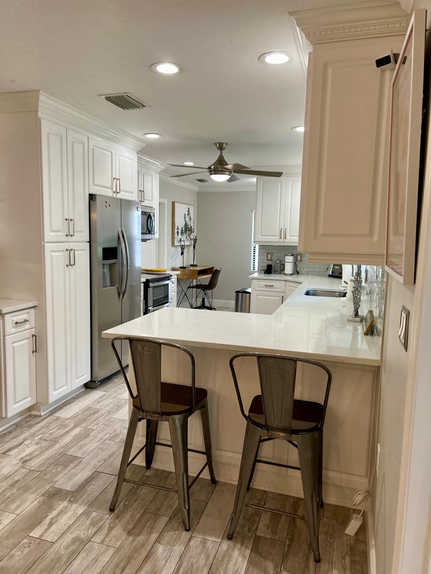 115 Northeast 18th Street Delray Beach, FL 33444 - Photo 10 of 36 a kitchen with stainless steel appliances a dining table chairs and sink