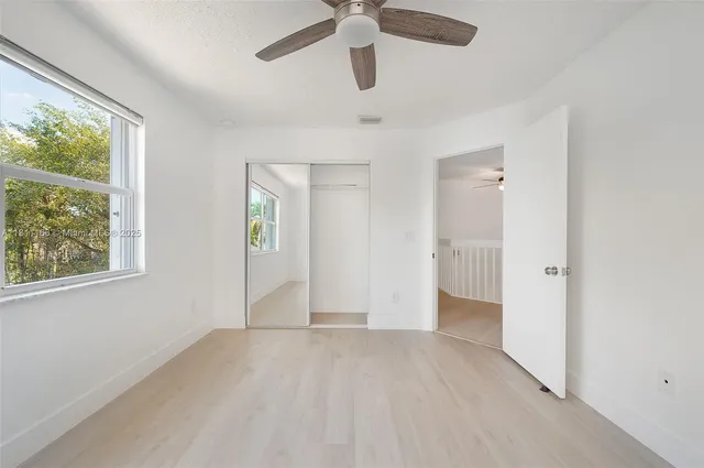 a view of an empty room with window and wooden floor