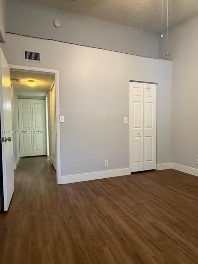 921 Lyons Road, Unit 3205 Coconut Creek, FL 33063 - Photo 12 of 37 an empty room with wooden floor and mirror