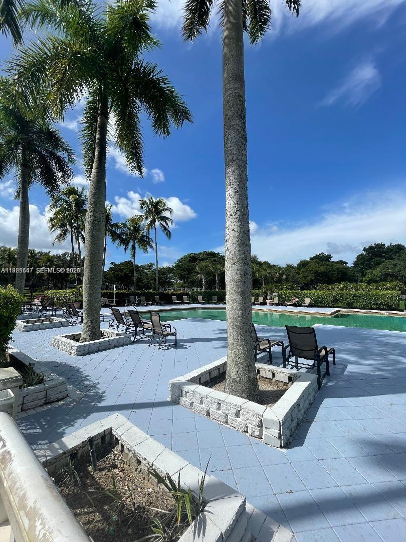 921 Lyons Road, Unit 3205 Coconut Creek, FL 33063 - Photo 27 of 37 a swimming pool with outdoor seating yard and palm tree