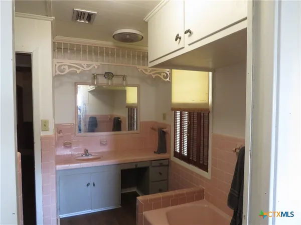 a bathroom with a tub sink and mirror