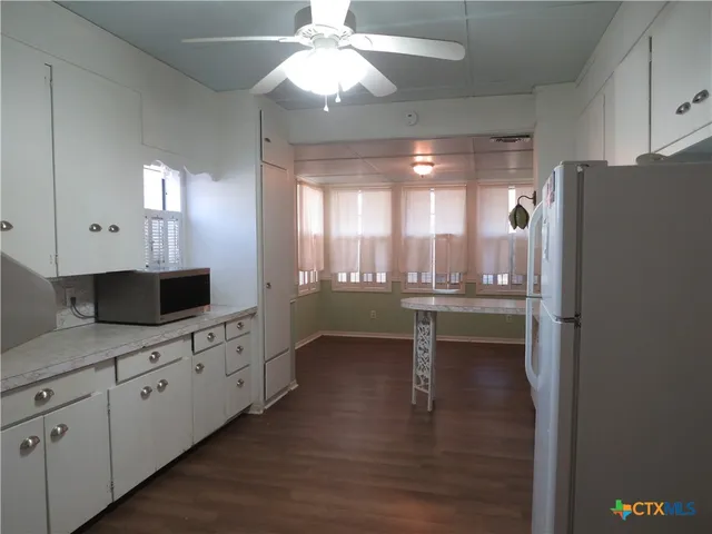 a kitchen with granite countertop a refrigerator a sink and dishwasher with wooden floor