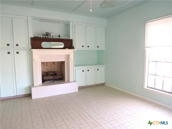 a view of an empty room with a fireplace and a window