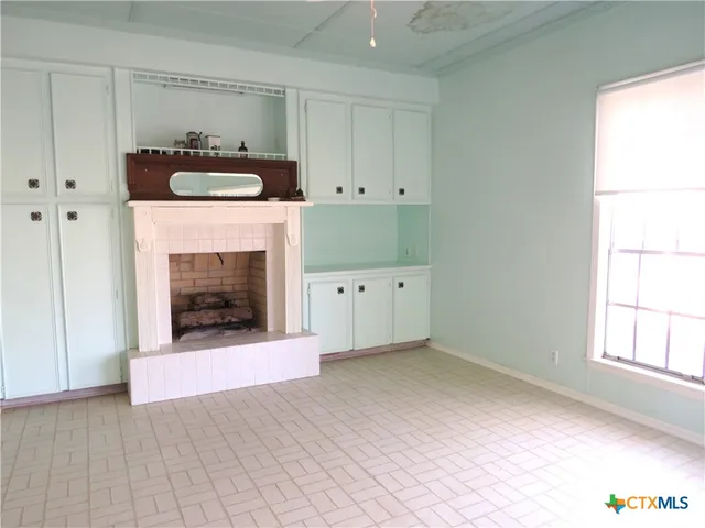 a view of an empty room with a fireplace and a window
