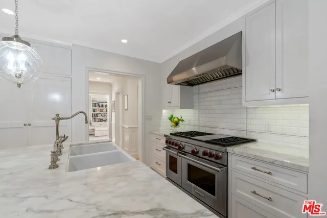 a kitchen with stainless steel appliances kitchen island granite countertop a sink a stove top oven a chimney and a center island