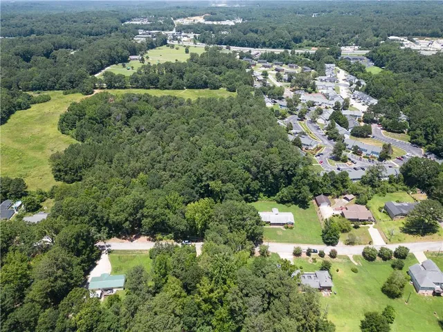 an aerial view of residential houses with outdoor space and trees