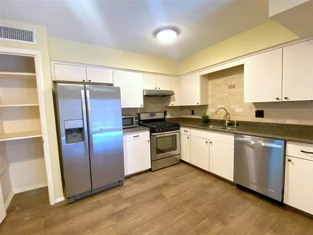 a kitchen with granite countertop a refrigerator and a sink