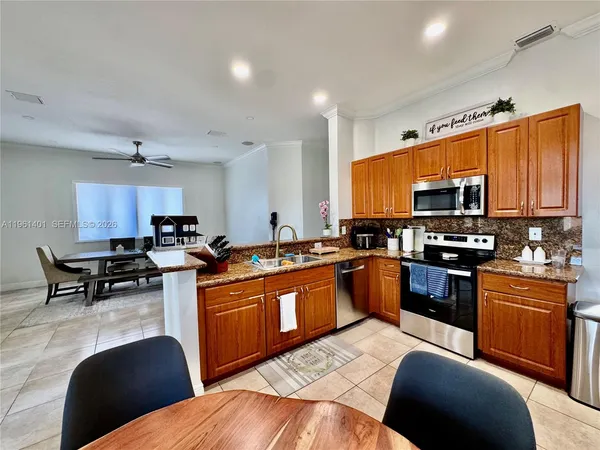 a kitchen with stainless steel appliances granite countertop a stove top oven a sink dishwasher a dining table and chairs with wooden floor