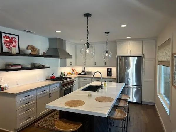 a kitchen with stainless steel appliances granite countertop a sink a stove a refrigerator and island with wooden floor