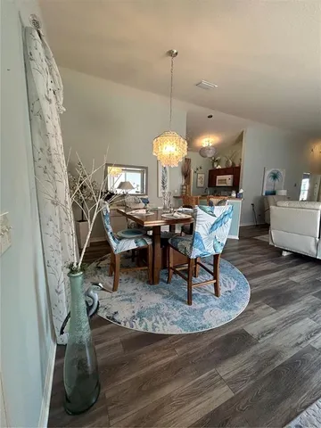 a living room with couches and a dining table with wooden floor