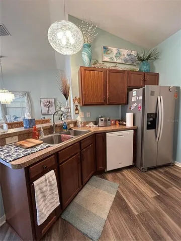 a kitchen with stainless steel appliances granite countertop a sink a stove a refrigerator cabinets and chairs