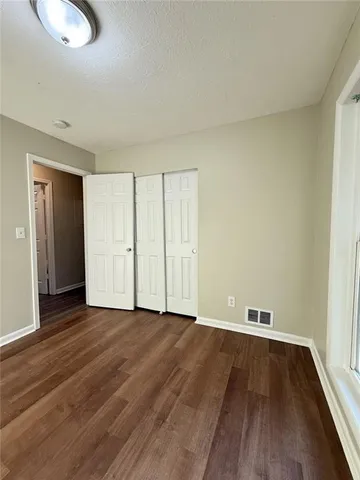 an empty room with wooden floor and closet