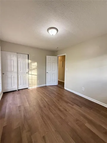 a view of an empty room with wooden floor and window