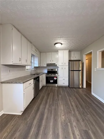 a kitchen with granite countertop a refrigerator and a stove top oven