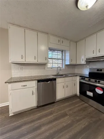 a kitchen with granite countertop white cabinets and white appliances