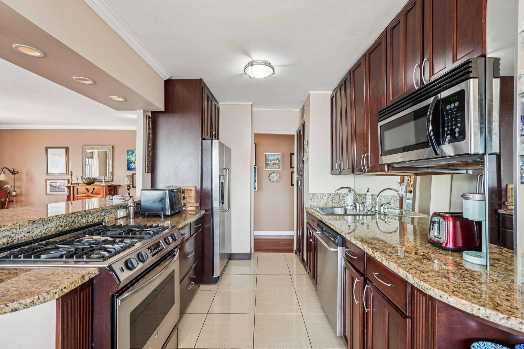 6040 Boulevard East, Unit 23G West New York, NJ 07093 - Photo 12 of 32 a kitchen with stainless steel appliances granite countertop a stove top oven a sink dishwasher and wooden cabinets with a granite countertops