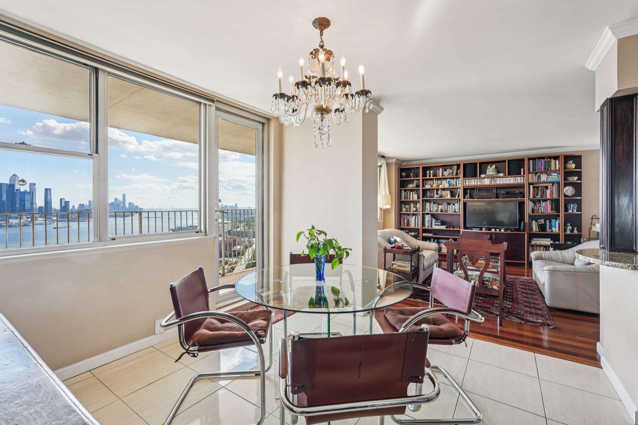 6040 Boulevard East, Unit 23G West New York, NJ 07093 - Photo 9 of 32 a living room with furniture a chandelier and a floor to ceiling window