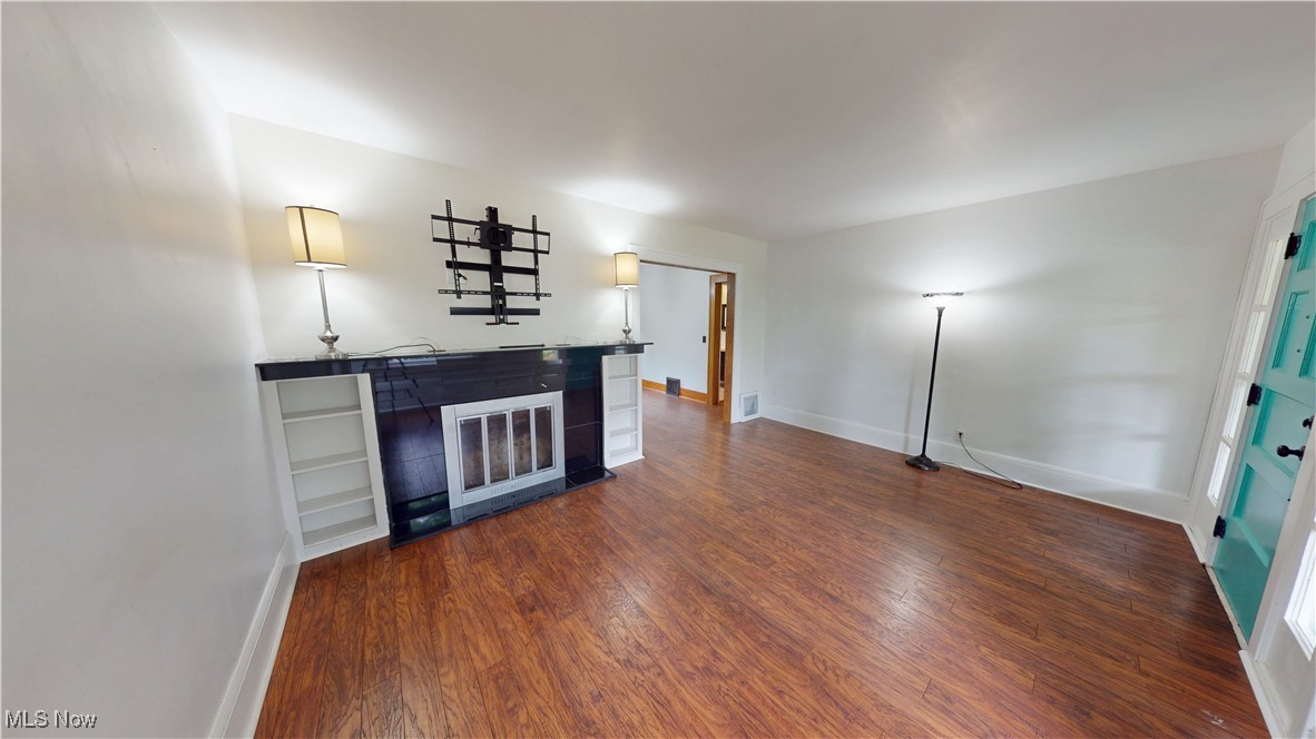 3261 Darrow Road Stow, OH 44224 - Photo 7 of 27 Unfurnished living room with dark wood-style flooring, baseboards, and bar area