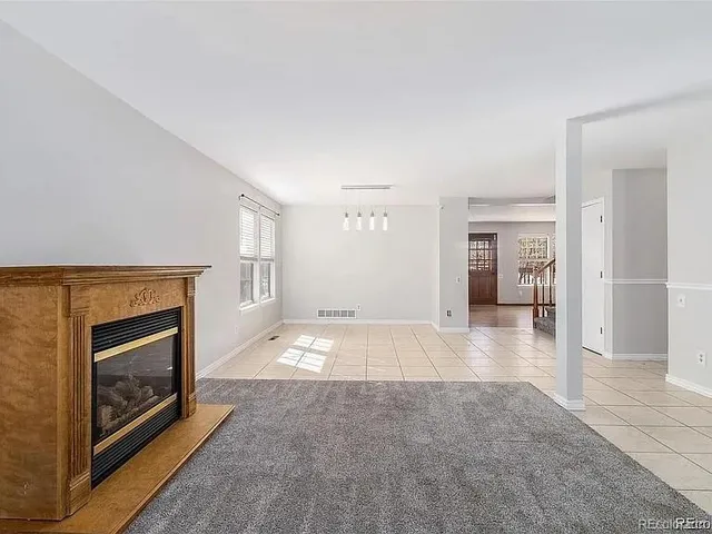 a view of empty room with kitchen and fireplace