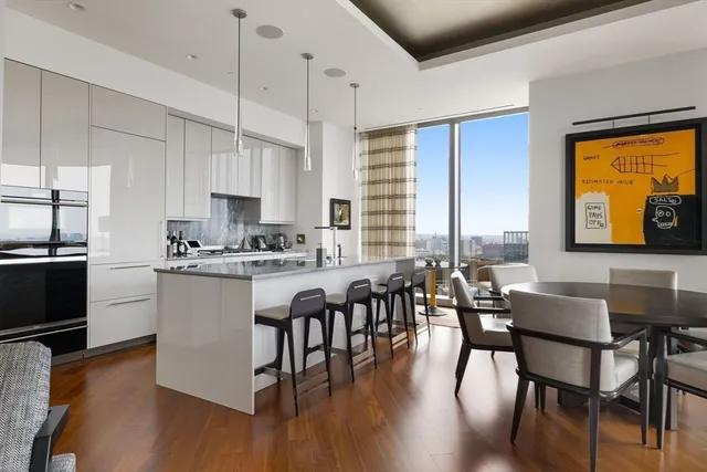 a kitchen with stainless steel appliances granite countertop a stove a refrigerator a kitchen island a dining table and chairs with wooden floor