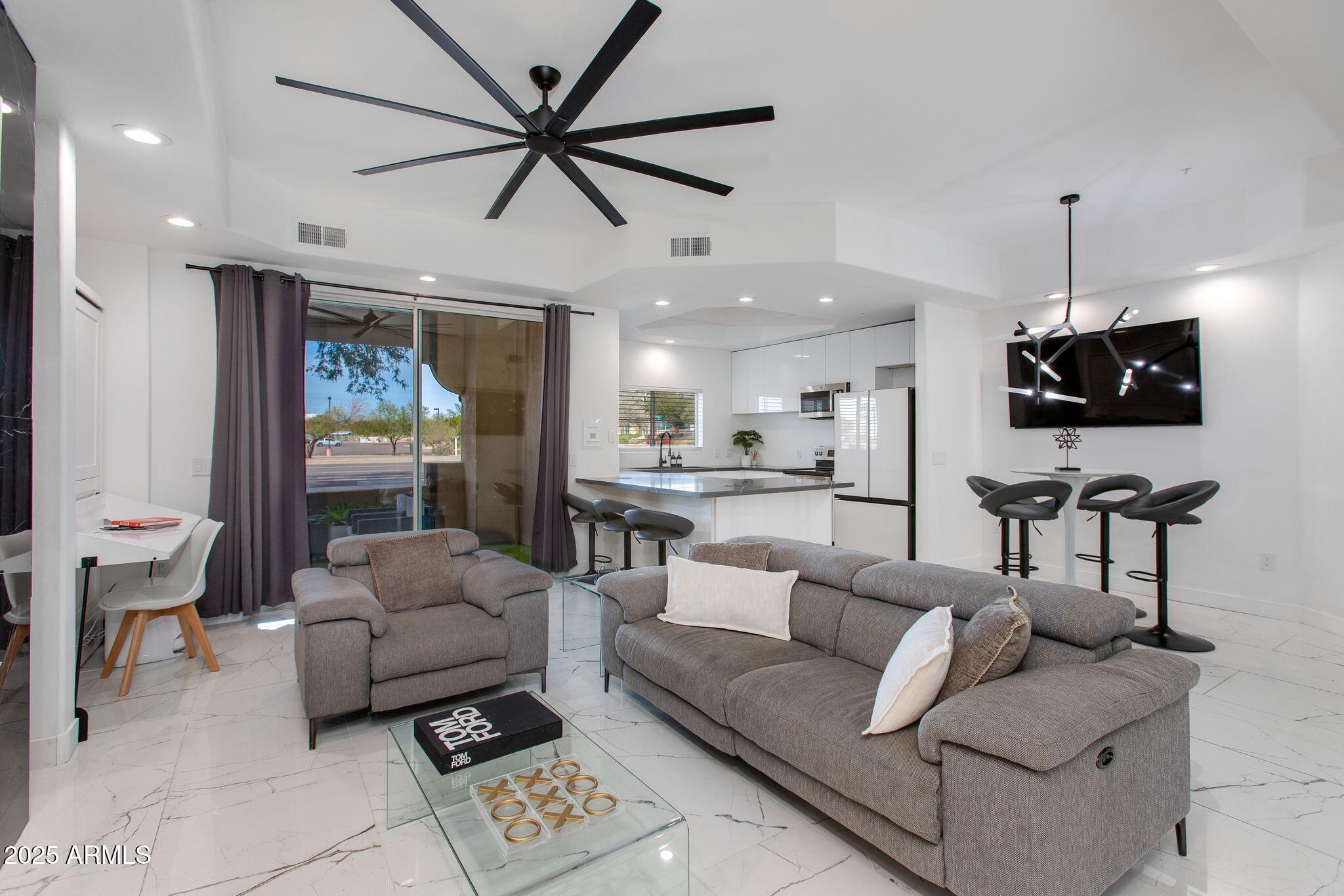 a living room with furniture a ceiling fan and a flat screen tv