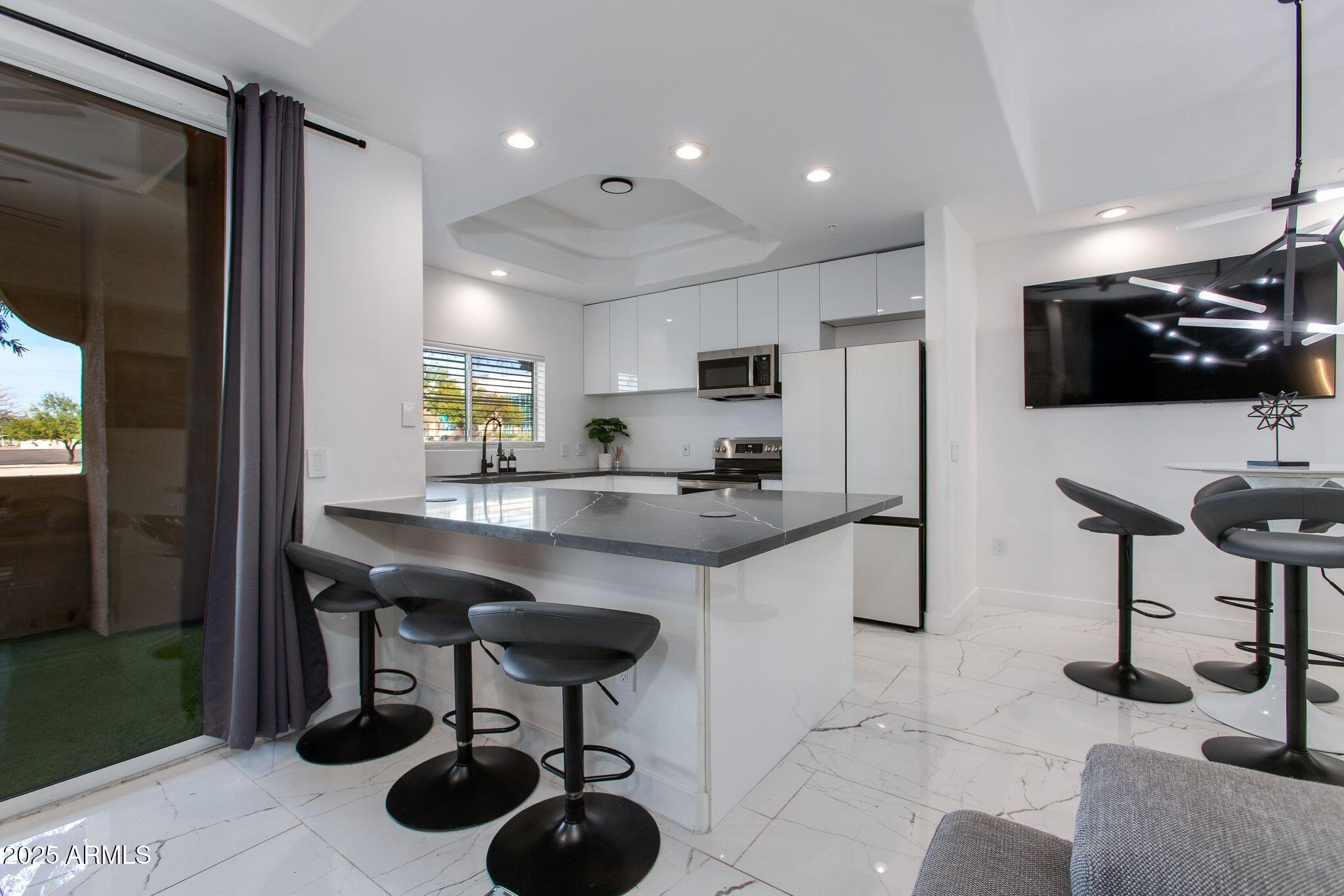 8245 East Bell Road, Unit 150 Scottsdale, AZ 85260 - Photo 3 of 12 a kitchen with stainless steel appliances granite countertop a sink a stove a refrigerator and chairs