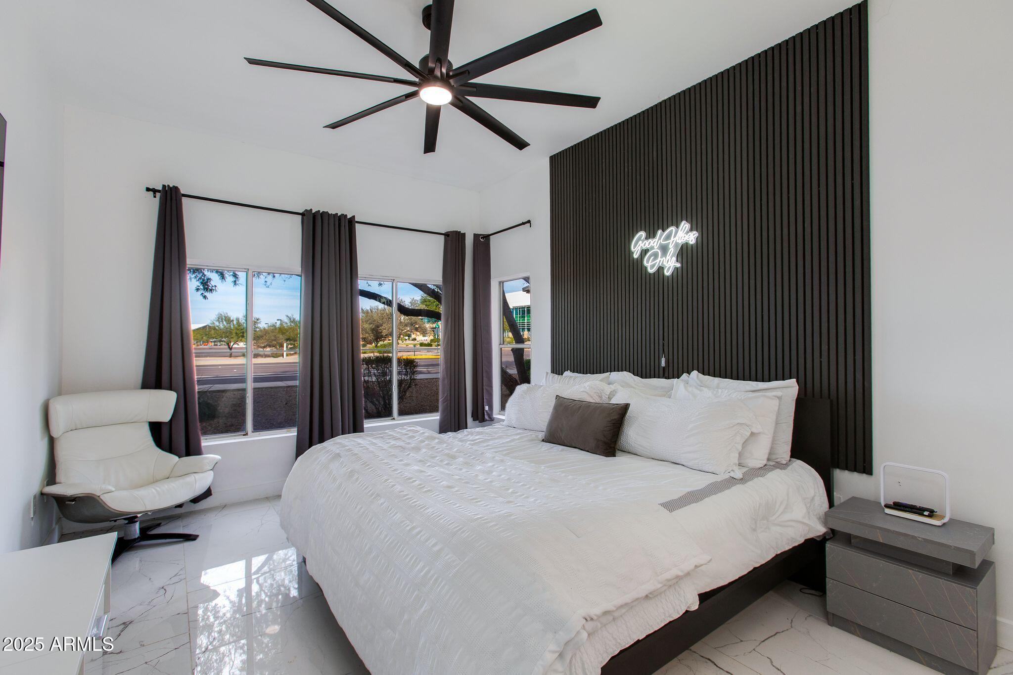 8245 East Bell Road, Unit 150 Scottsdale, AZ 85260 - Photo 5 of 12 a bedroom with a bed a couch and a chandelier