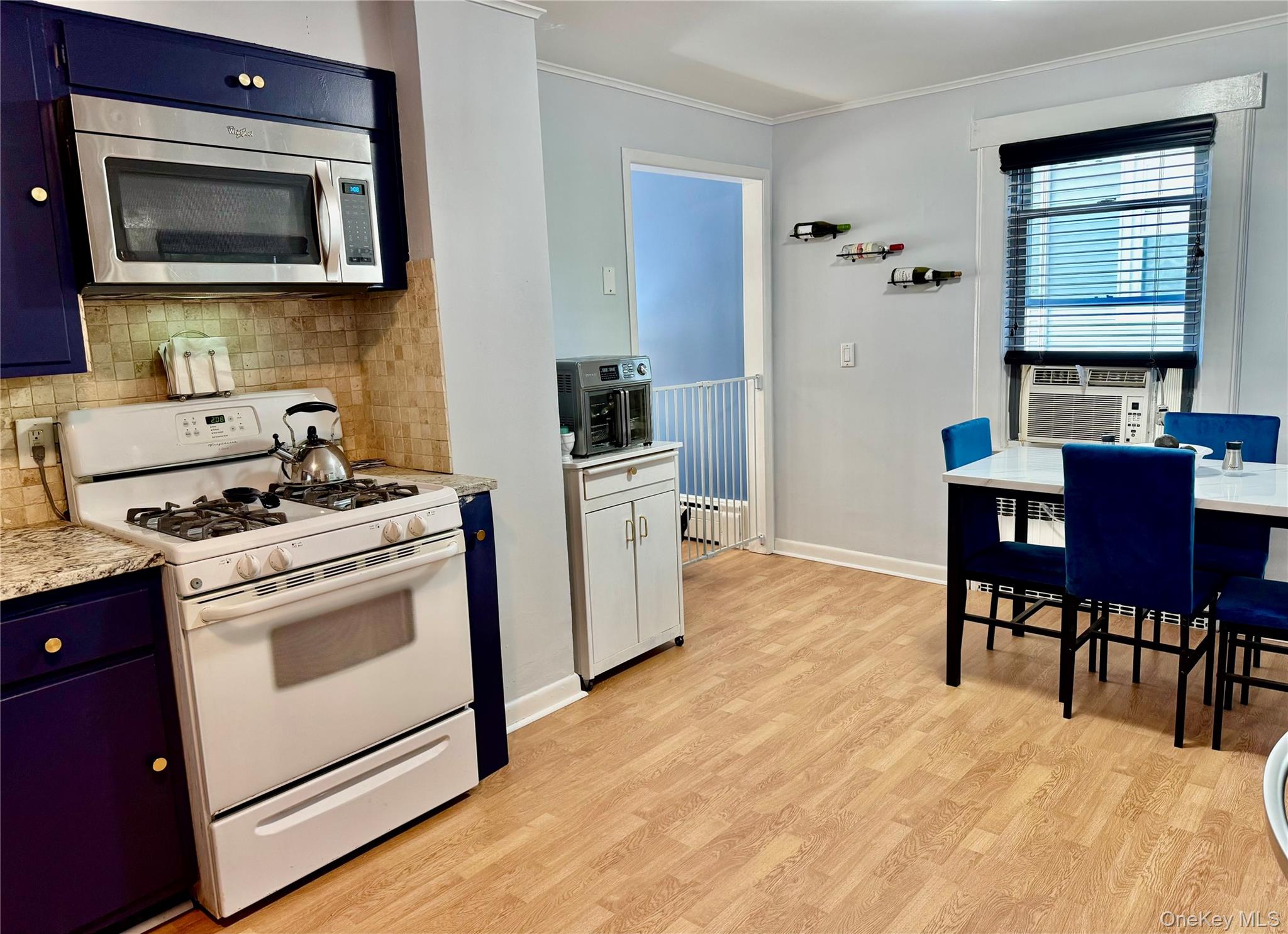 25 School Street Port Washington, NY 11050 - Photo 19 of 25 Kitchen featuring blue cabinets, white range with gas stovetop, decorative backsplash, stainless steel microwave, and crown molding