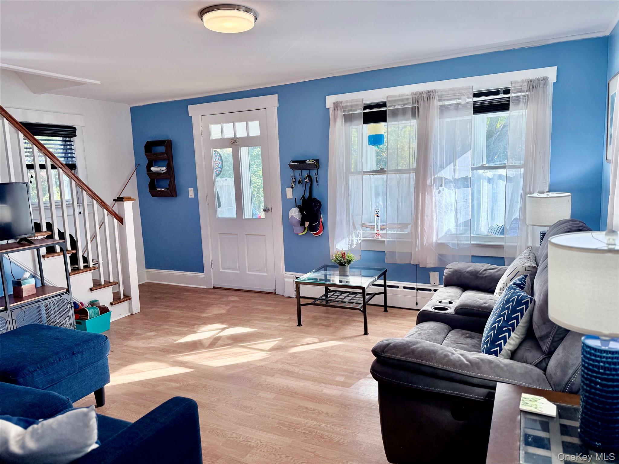25 School Street Port Washington, NY 11050 - Photo 6 of 25 Living area with light wood-type flooring, stairs, and a baseboard heating unit