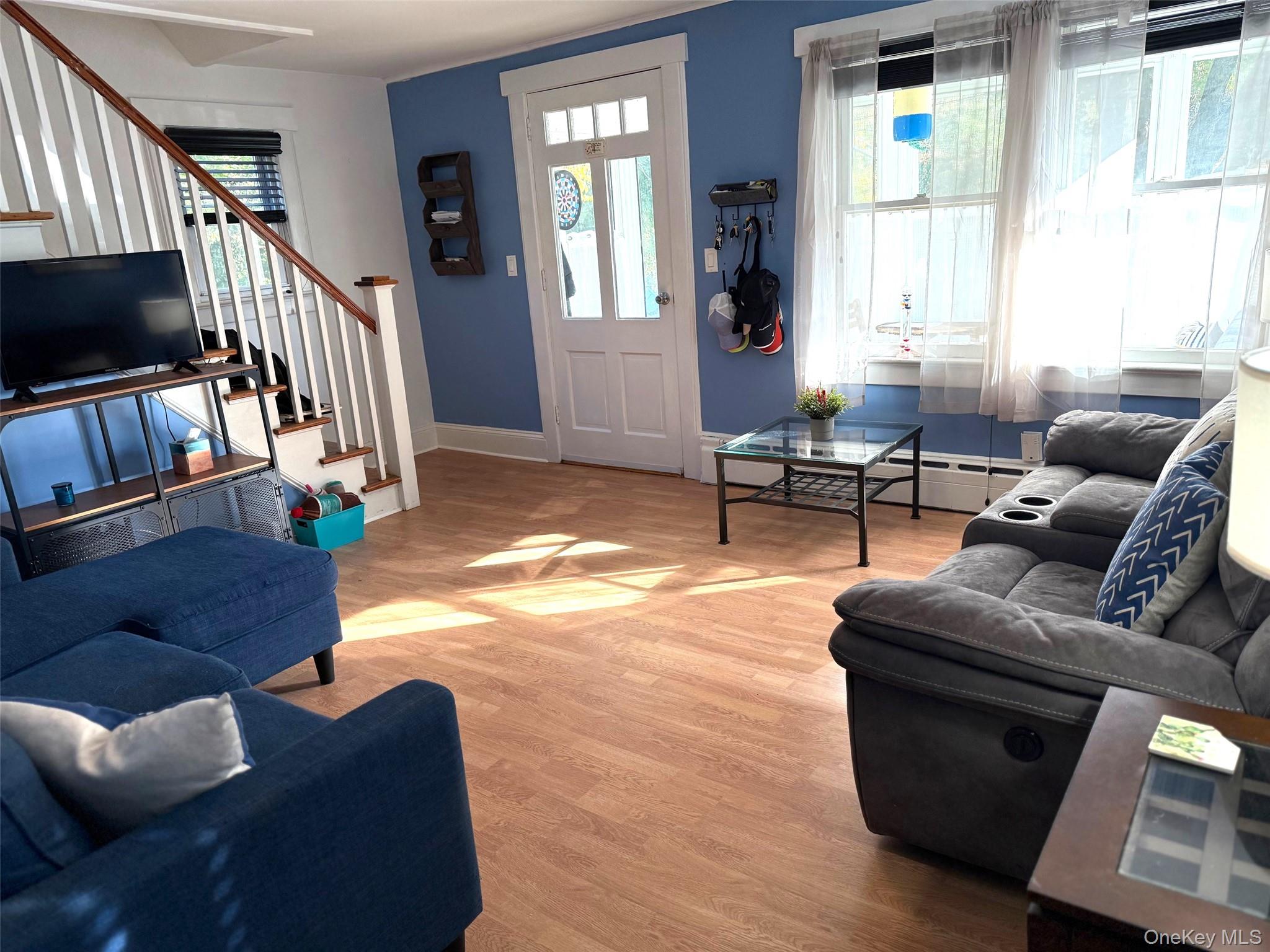 25 School Street Port Washington, NY 11050 - Photo 8 of 25 Living room featuring light wood-style floors, stairway, and baseboard heating